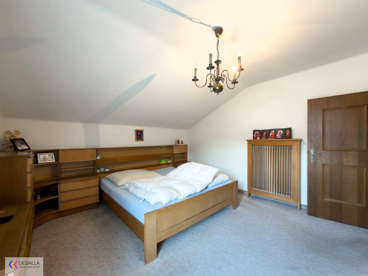 Geräumiges Schlafzimmer mit Holzmöbeln, Doppelbett und einer charakteristischen Dachschräge.