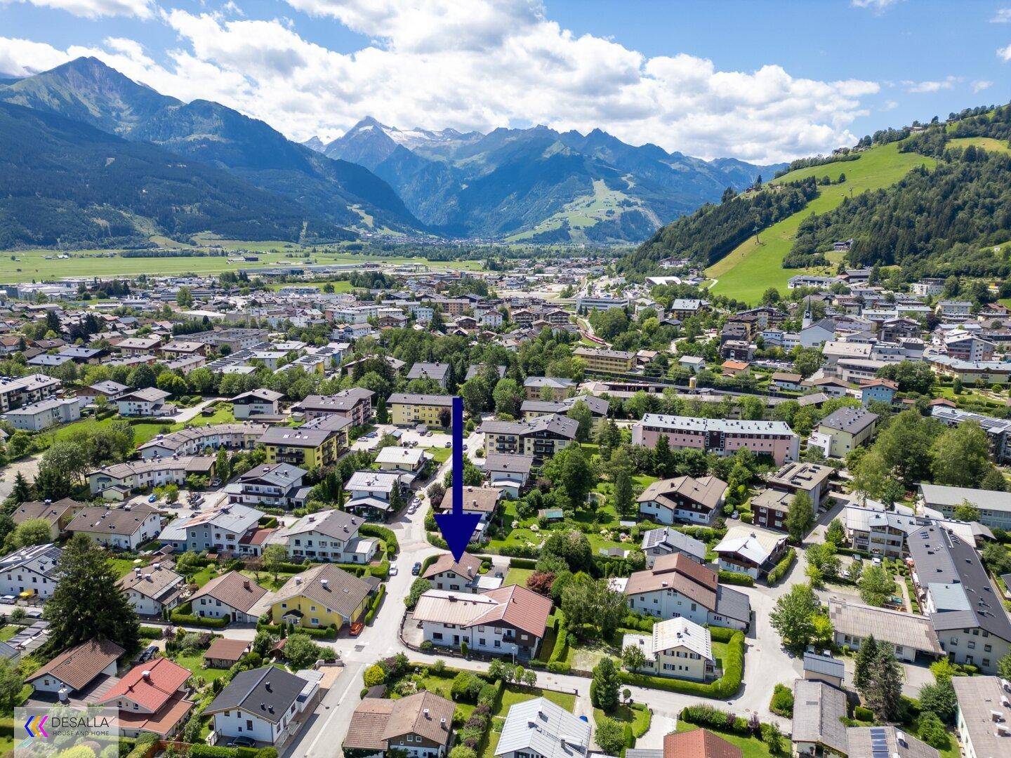 Weitläufige Luftaufnahme des Hauses in einer Wohnsiedlung mit beeindruckender Bergkulisse.