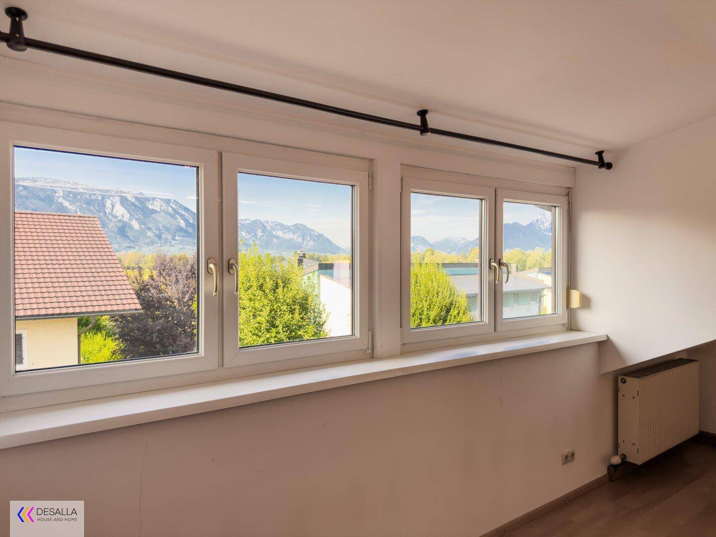 Helles Zimmer mit Bergblick durch große Fenster und schrägen Wänden.
