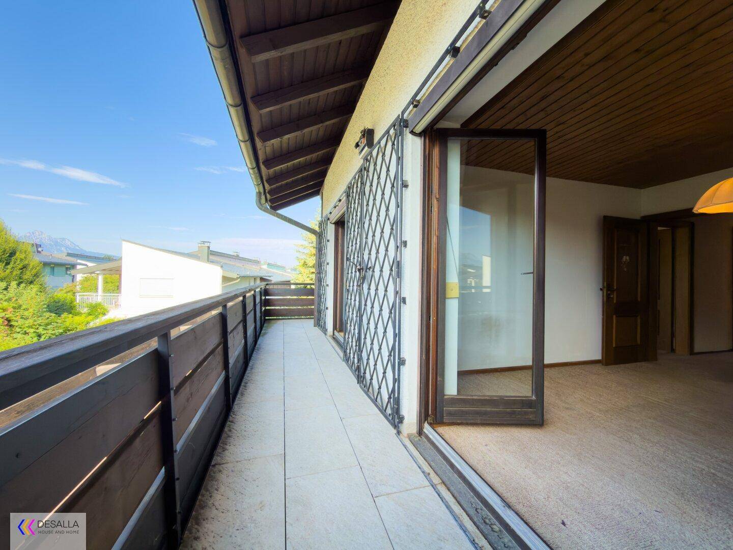 Langer Balkon mit Fliesenboden und Metallgeländer, zugänglich von Innenräumen.