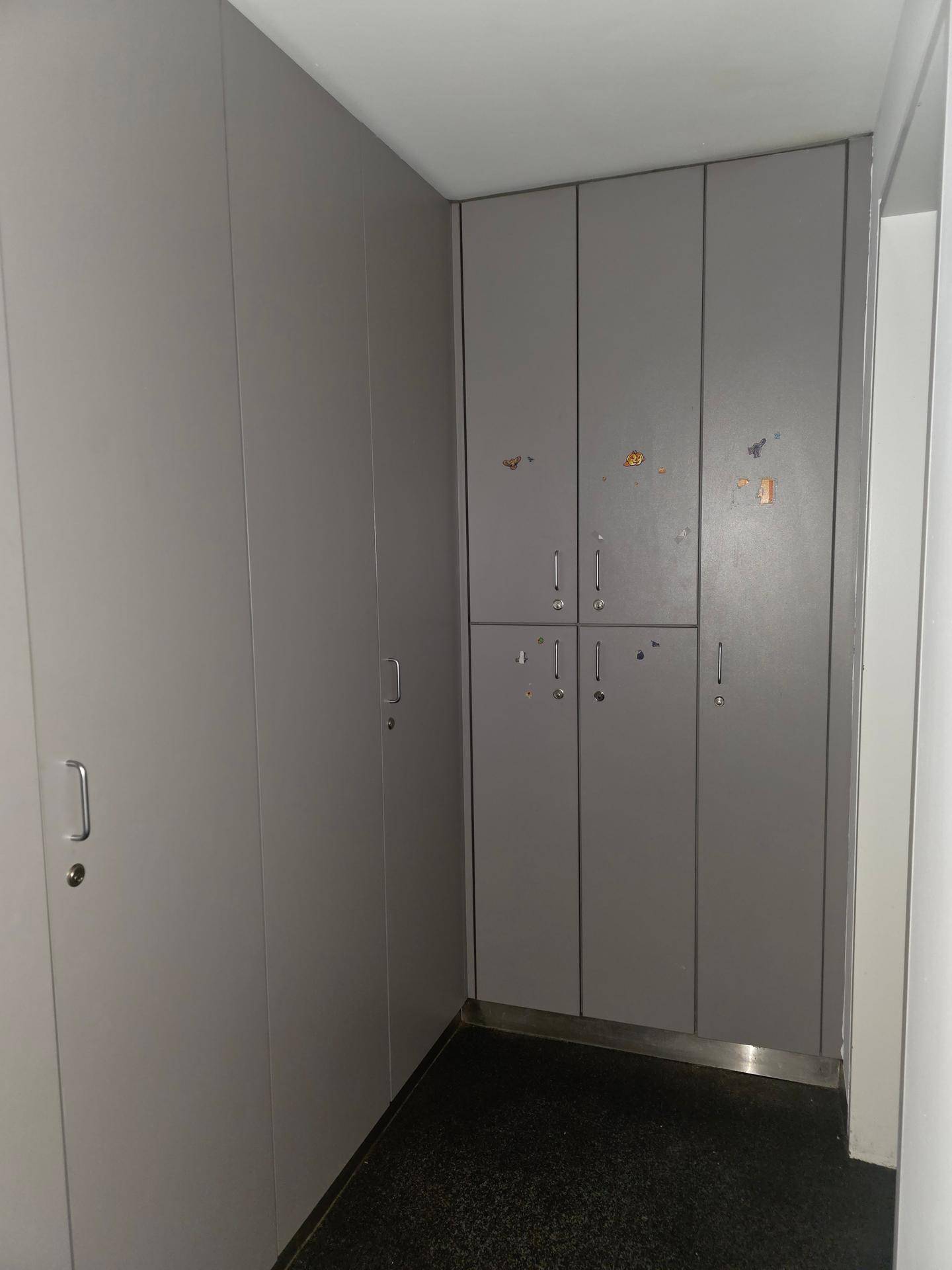 Raum mit grauen, eingebauten Spinden oder Lagerschränken, die praktischen Stauraum bieten.