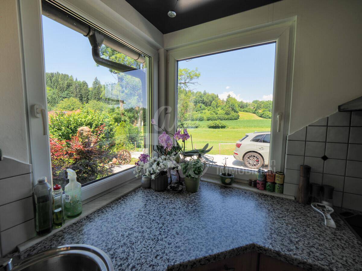 Küche mit Granitarbeitsplatte und großem Fenster mit Blick ins Grüne.