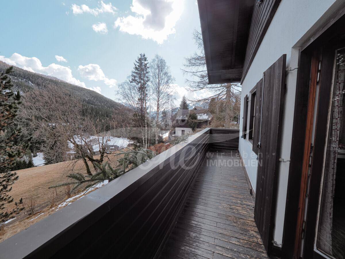 Geräumiger Holzbalkon mit weitem Blick über die alpine Landschaft.