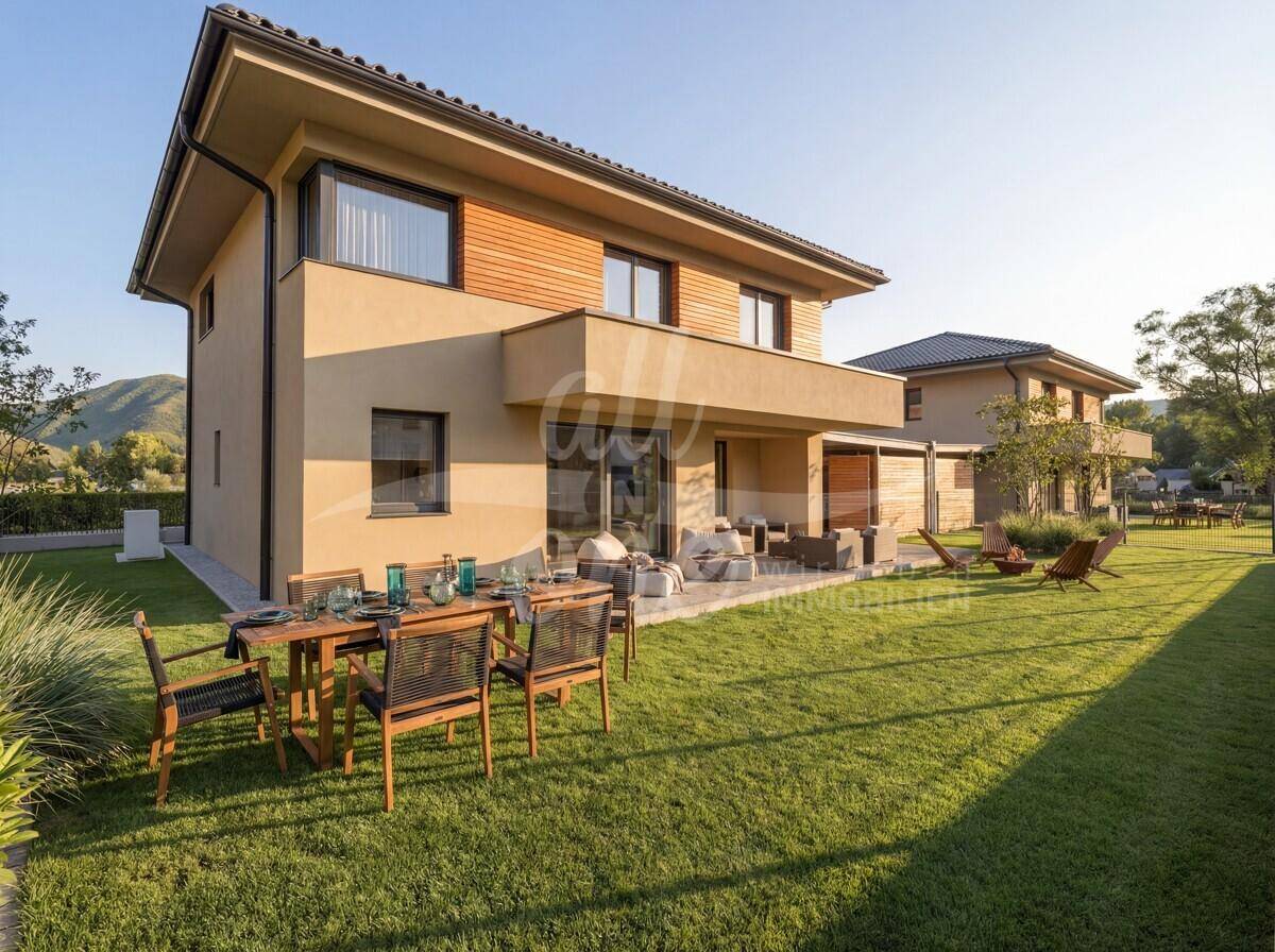 Weitläufiger Gartenbereich mit großer Terrasse, Essplatz und Liegestühlen vor moderner Hausfassade.