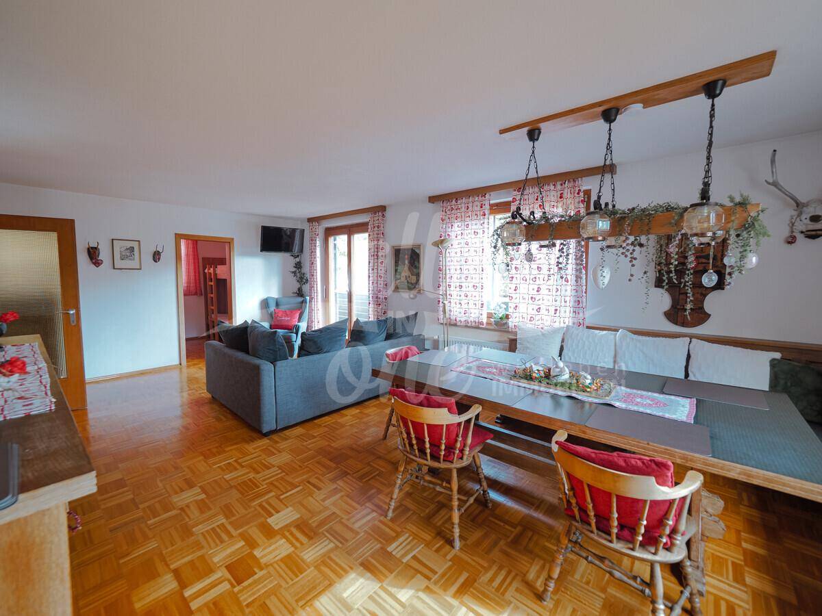 Heller Wohn-Essbereich mit Parkettboden, großem Esstisch und Zugang zum Balkon.
