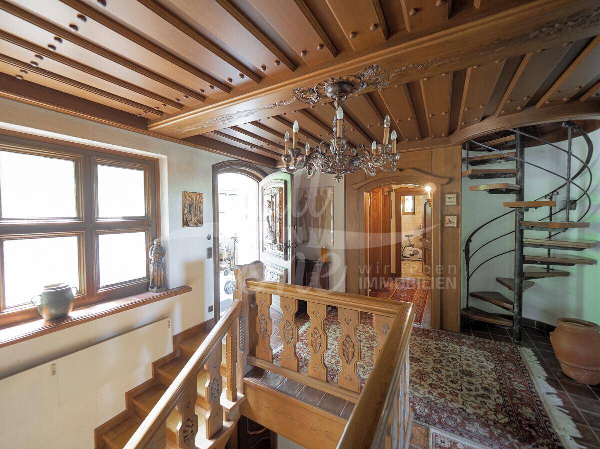 Geräumiger Flur mit Holztreppe, Wendeltreppe und einer beeindruckenden Holzbalkendecke.