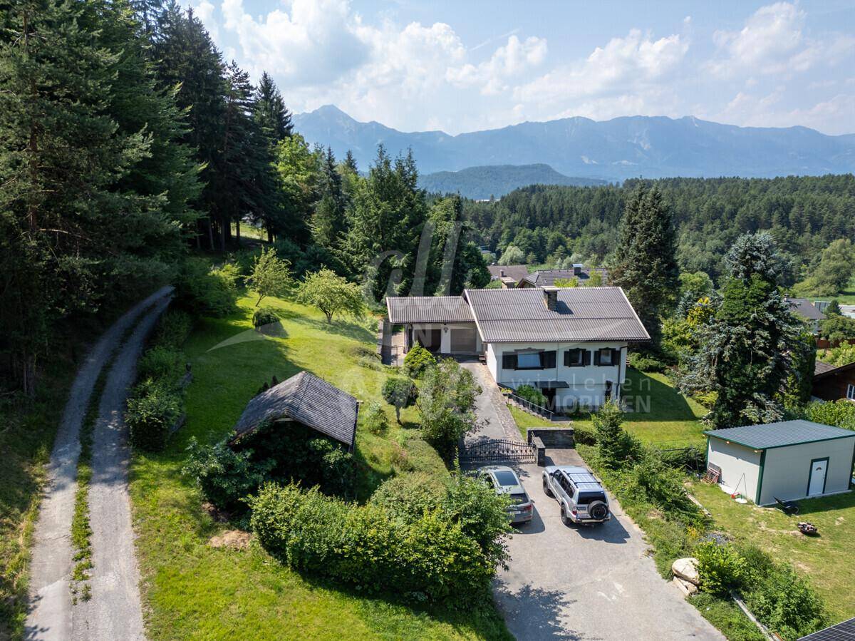 Weitläufige Luftaufnahme des Anwesens mit Zufahrt, umgeben von Natur und Bergblick im Hintergrund.