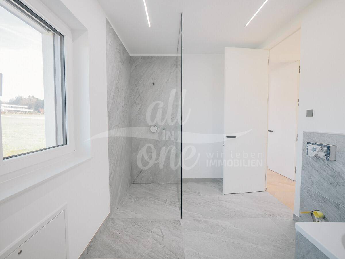 Modernes Badezimmer mit ebenerdiger Dusche, großformatigen Fliesen und Fenster für Tageslicht.