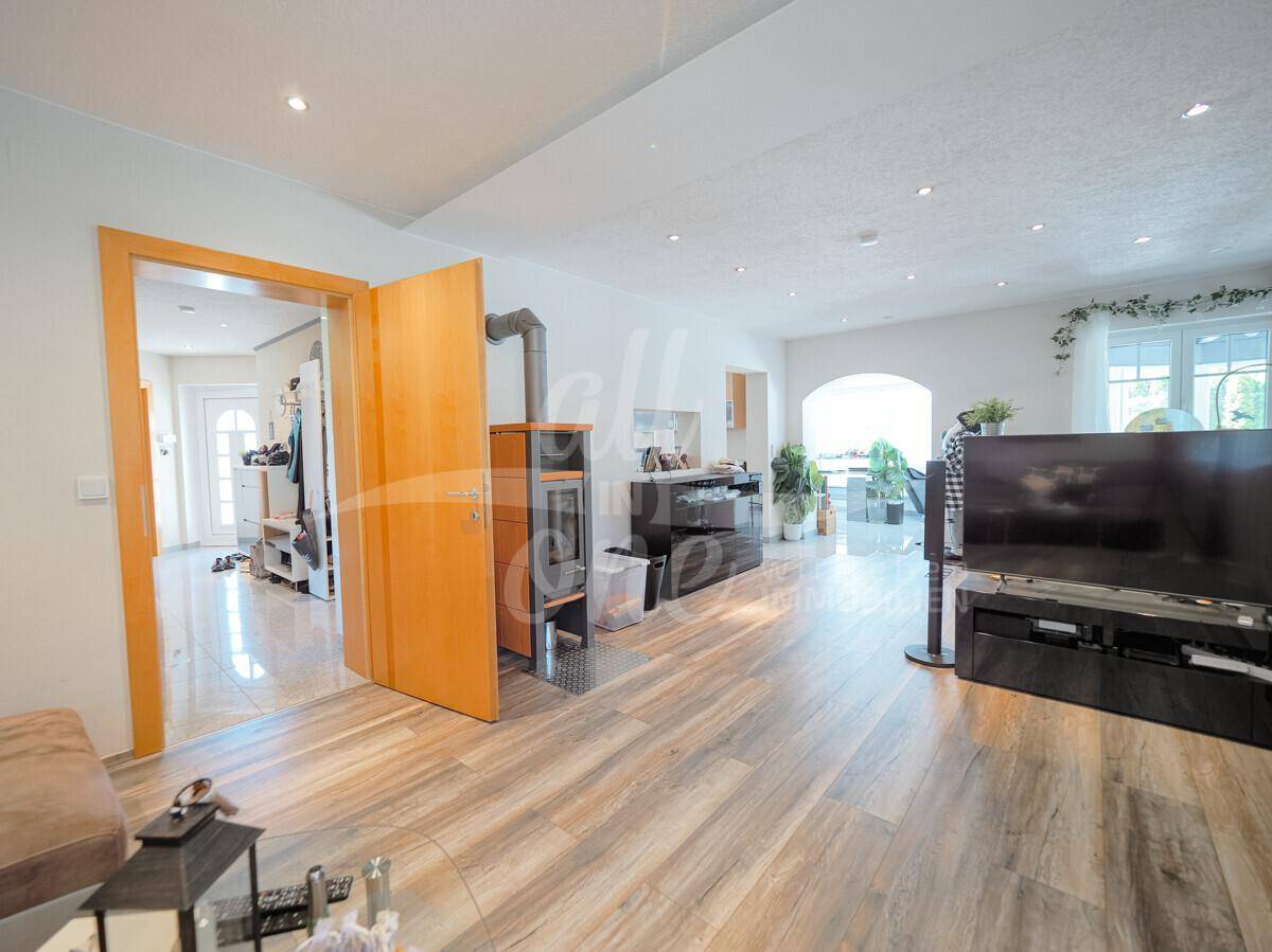 Geräumiges Wohnzimmer mit Laminatboden, einem gemütlichen Holzofen und Zugang zum Flur.