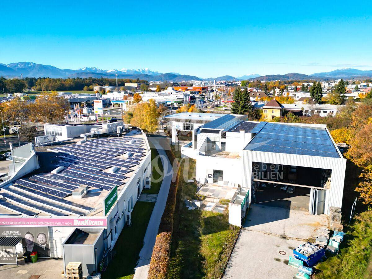 Überblick über ein Gewerbeareal mit mehreren Gebäuden, Solaranlagen und umliegender Infrastruktur.