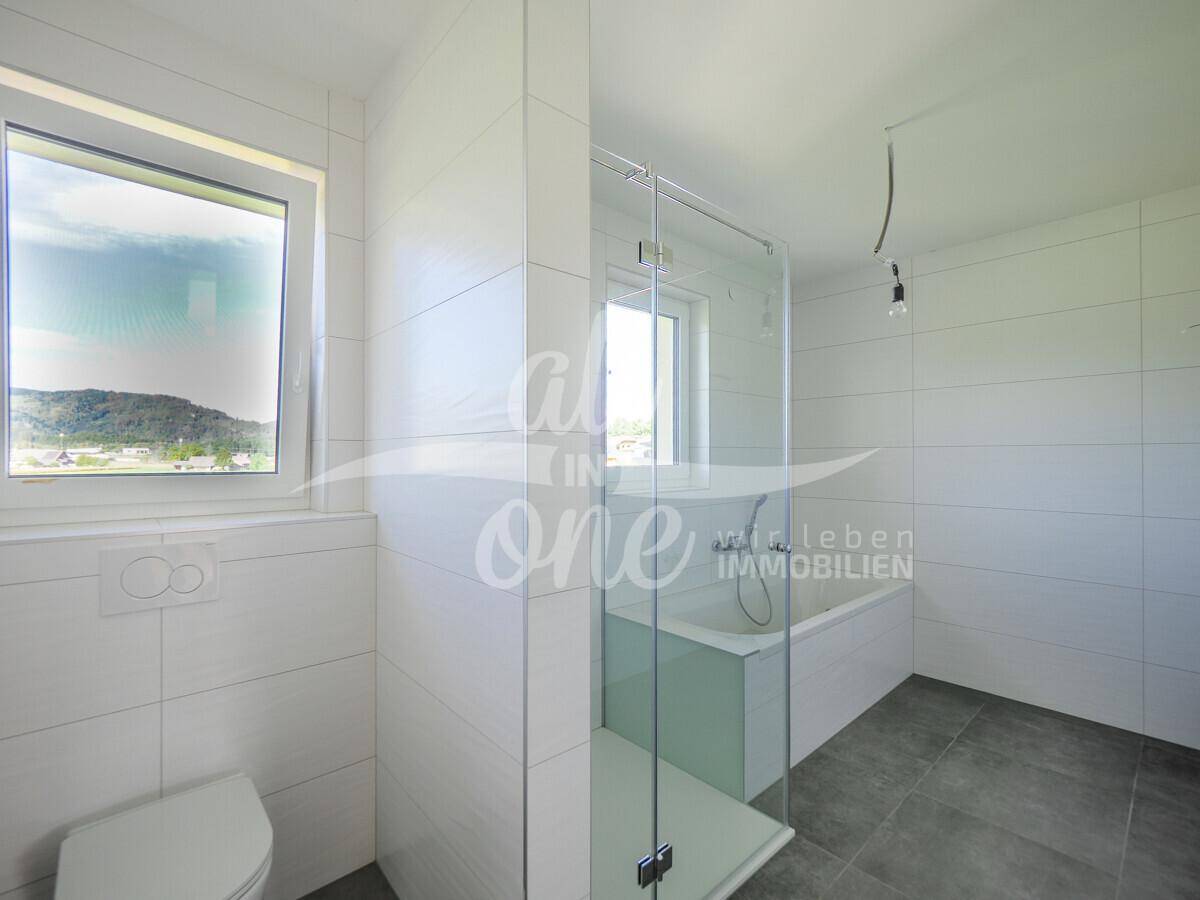 Modernes Badezimmer mit weißen Fliesen, Dusche und Badewanne sowie Fenster für natürliche Belüftung.