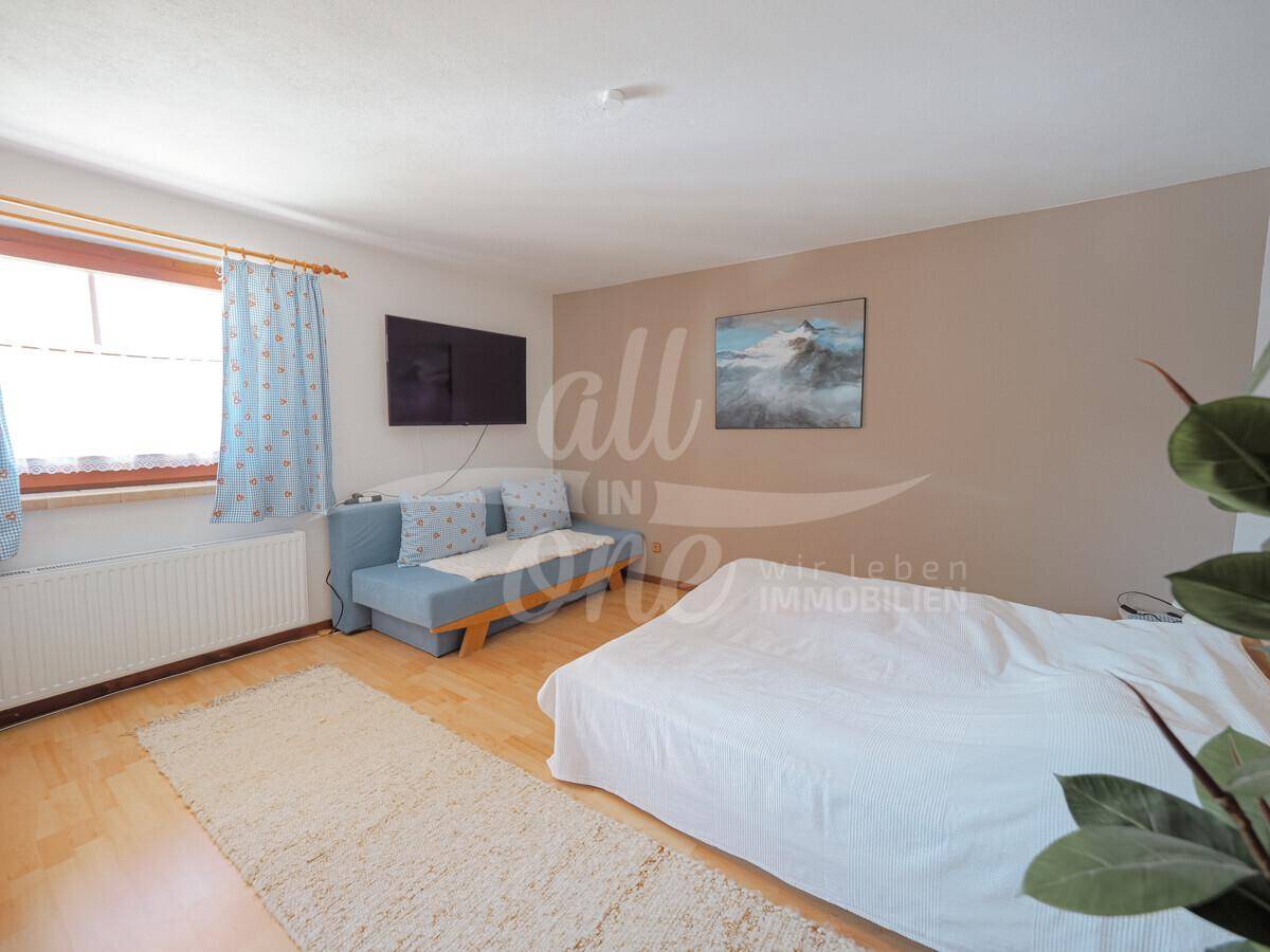 Helles Schlafzimmer mit Doppelbett, Sofa und Holzboden.