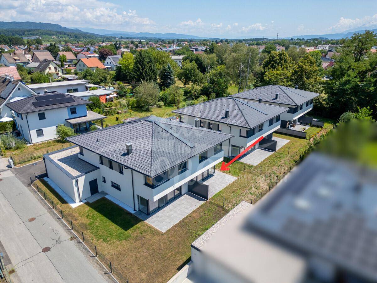 Panoramablick auf eine Reihe moderner Häuser mit Gärten und Terrassen in einer ruhigen Wohngegend.