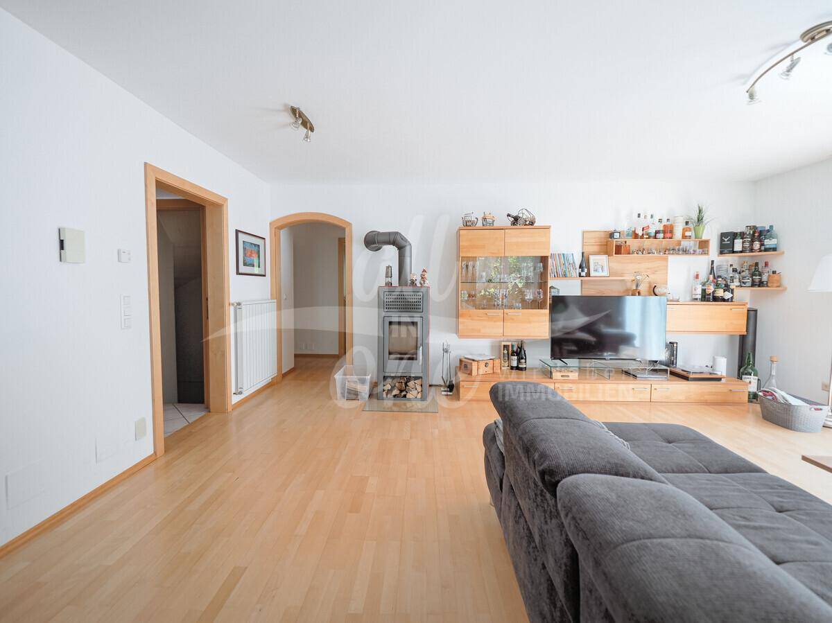 Geräumiges Wohnzimmer mit Holzboden, Kaminofen und Holzmöbeln.