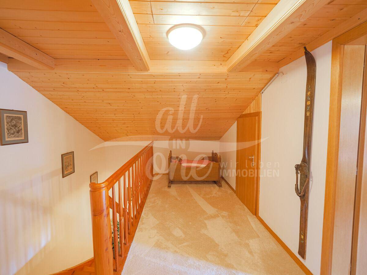 Heller Flur im Obergeschoss mit Holzdecke und Blick auf die Treppe.