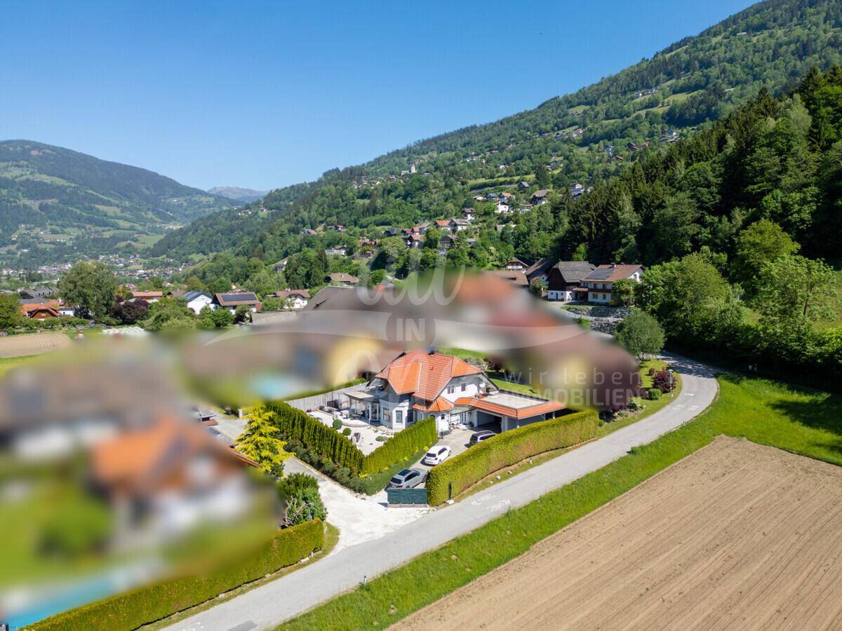 Weitläufige Luftaufnahme des Anwesens in ländlicher Umgebung mit Feldern und bewaldeten Bergen.