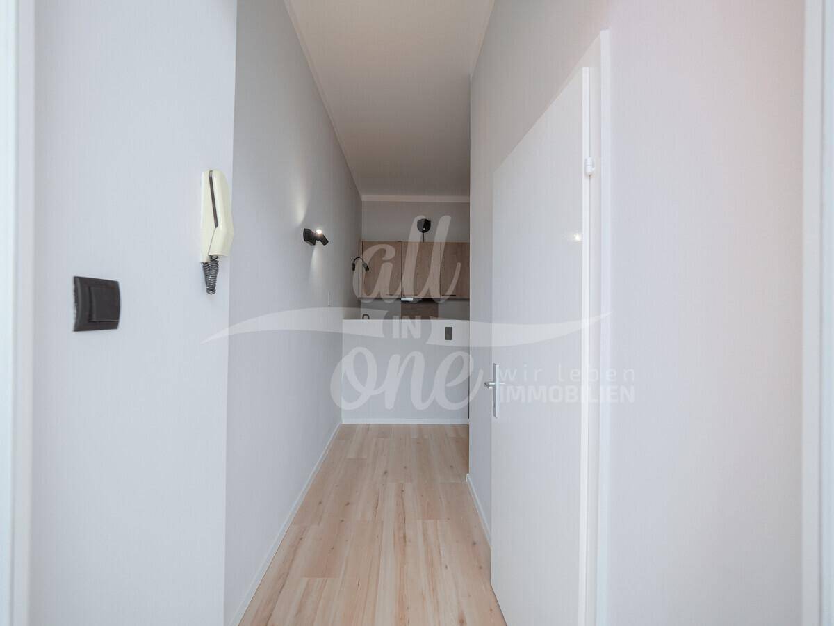 Heller Flur mit Laminatboden und Blick in die offene Küchenzeile.