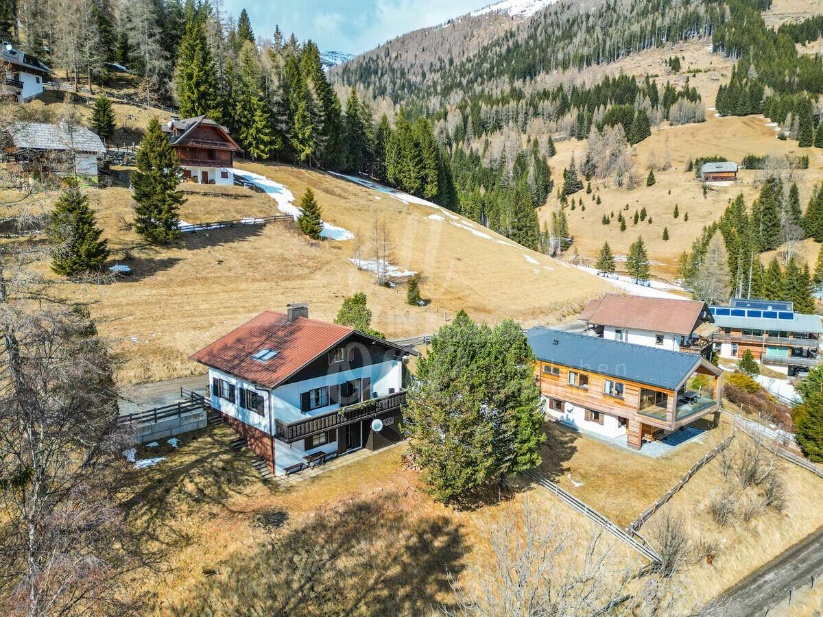 Weitläufige Ansicht des Hauses in einer sonnigen Berglandschaft mit vereinzelten Schneeresten.