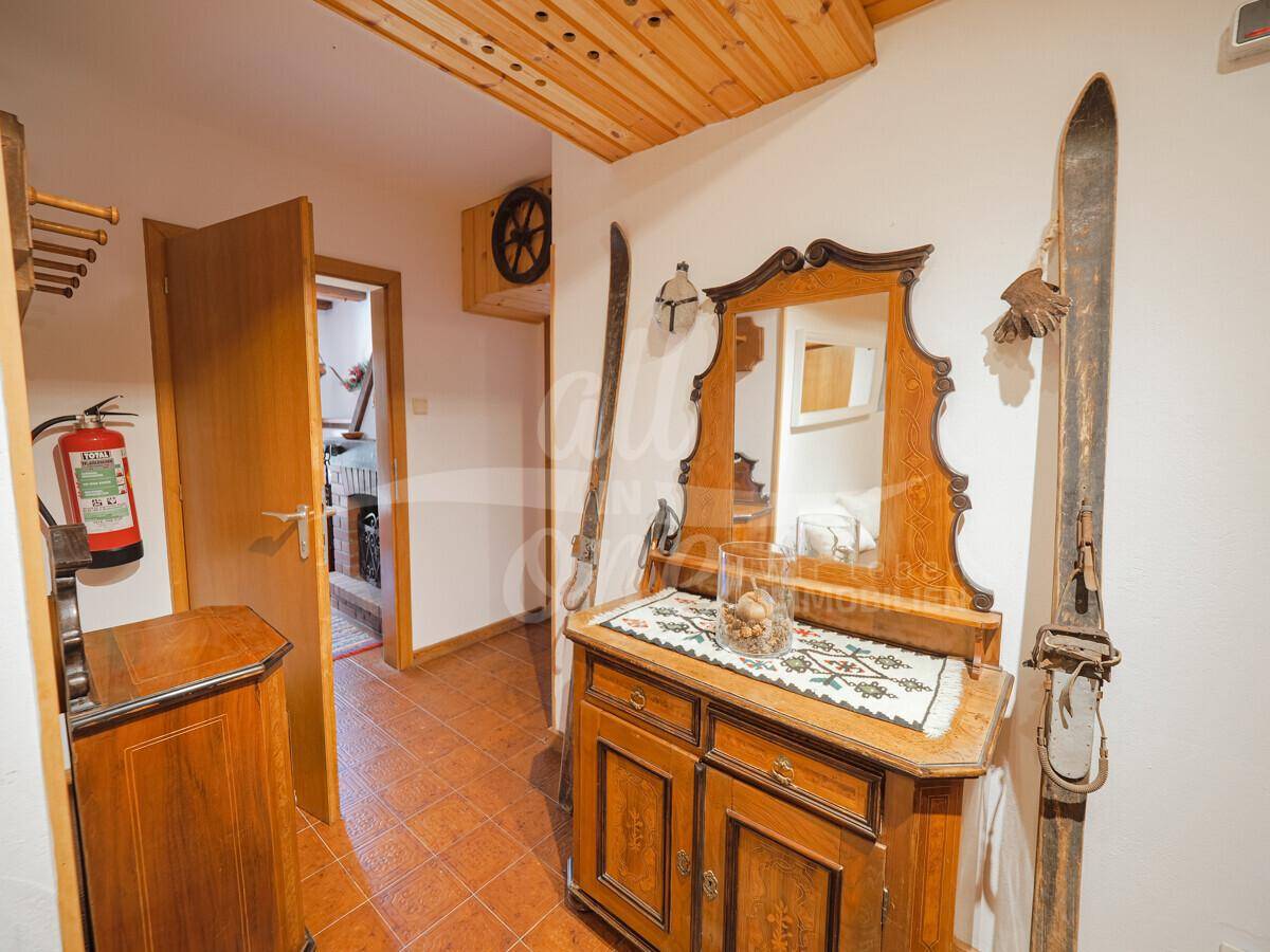 Rustikaler Eingangsbereich mit Holzdecke, Fliesenboden und traditionellen Dekorationen.