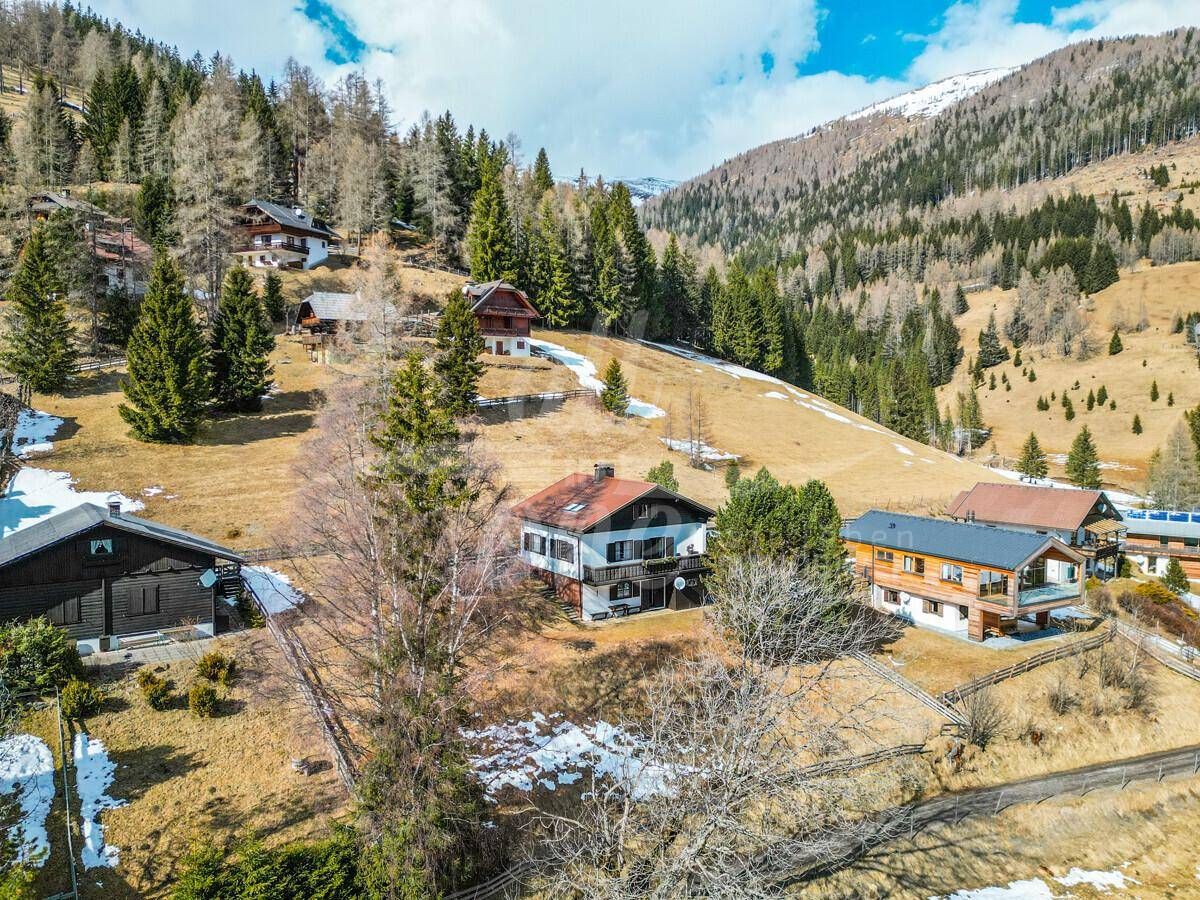 Luftaufnahme des Hauses und der Nachbarschaft in einer alpinen Frühlingslandschaft.