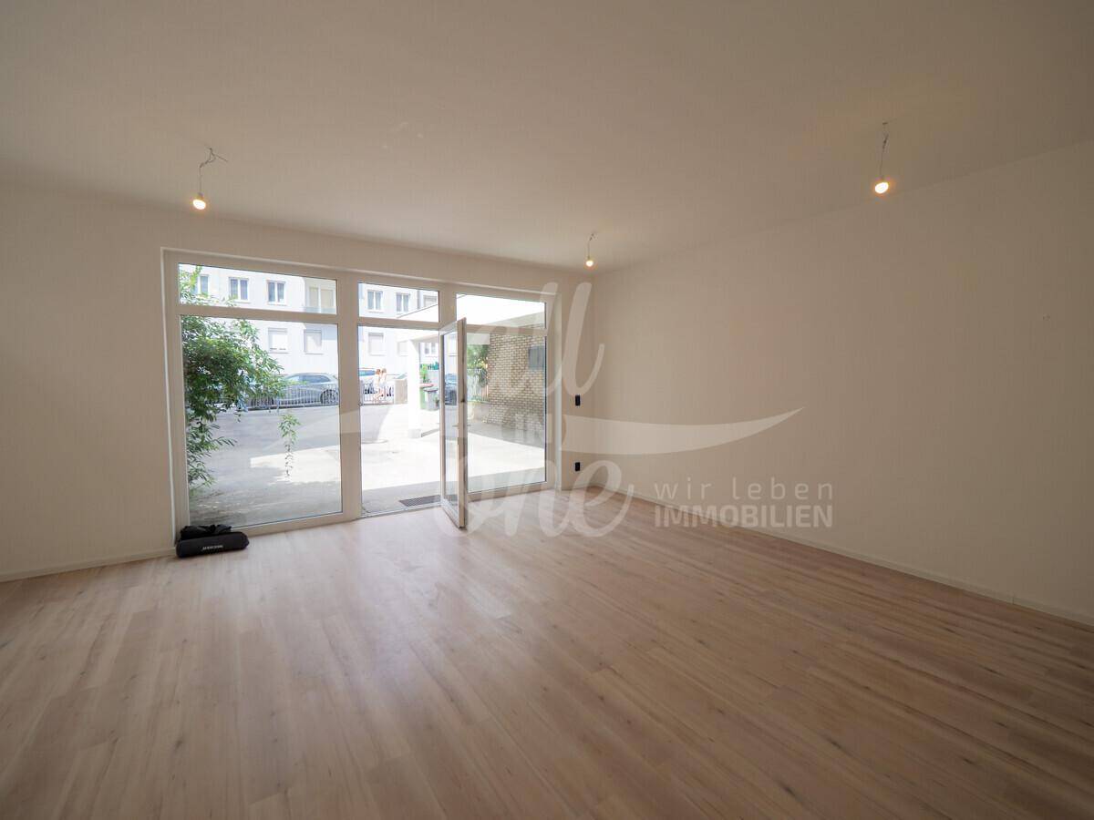 Geräumiger, heller Raum mit Laminatboden und großen Fenstern zum Außenbereich.