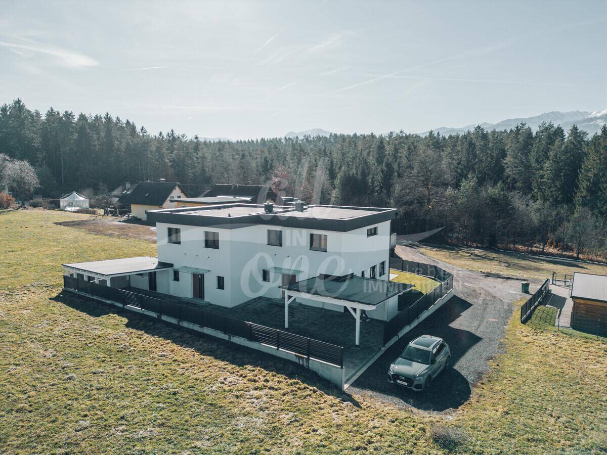 Weitläufige Luftaufnahme des Hauses mit Carport und umgebender Naturlandschaft.