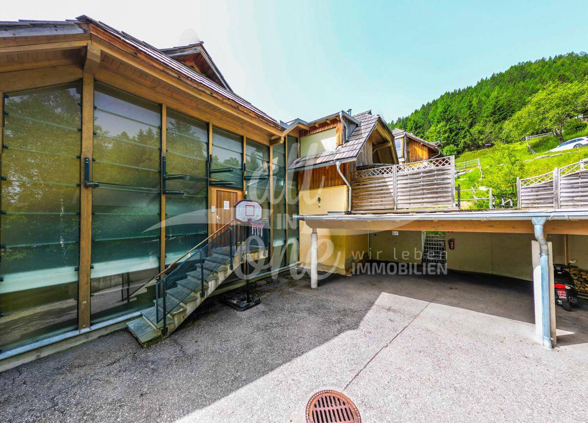 Moderne Architektur mit Glasfassade, Holzverkleidung und überdachtem Parkbereich.
