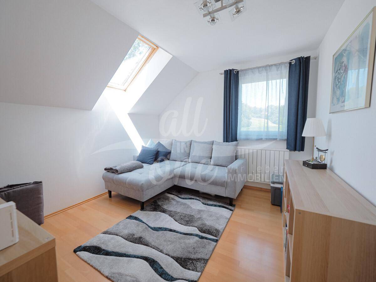 Helles Wohnzimmer mit Sofa, Dachfenster und Holzboden.