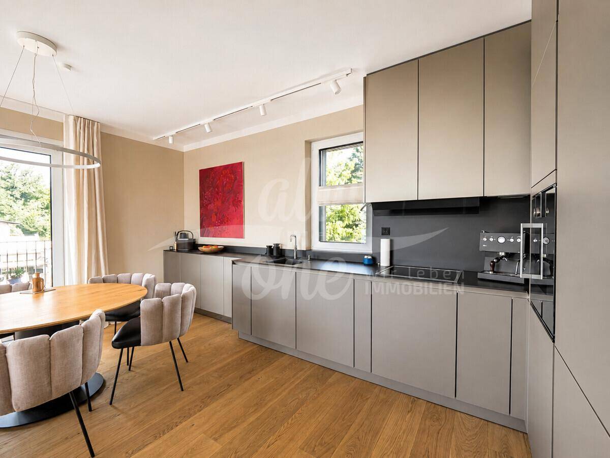 Moderne Küche mit grauen Schränken, Holzboden und Essbereich, hell durch ein großes Fenster.