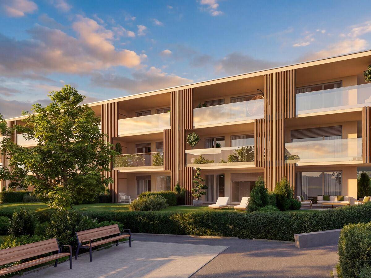 Moderne Wohnanlage mit Balkonen, Terrassen und gepflegten Grünflächen mit Sitzbänken.
