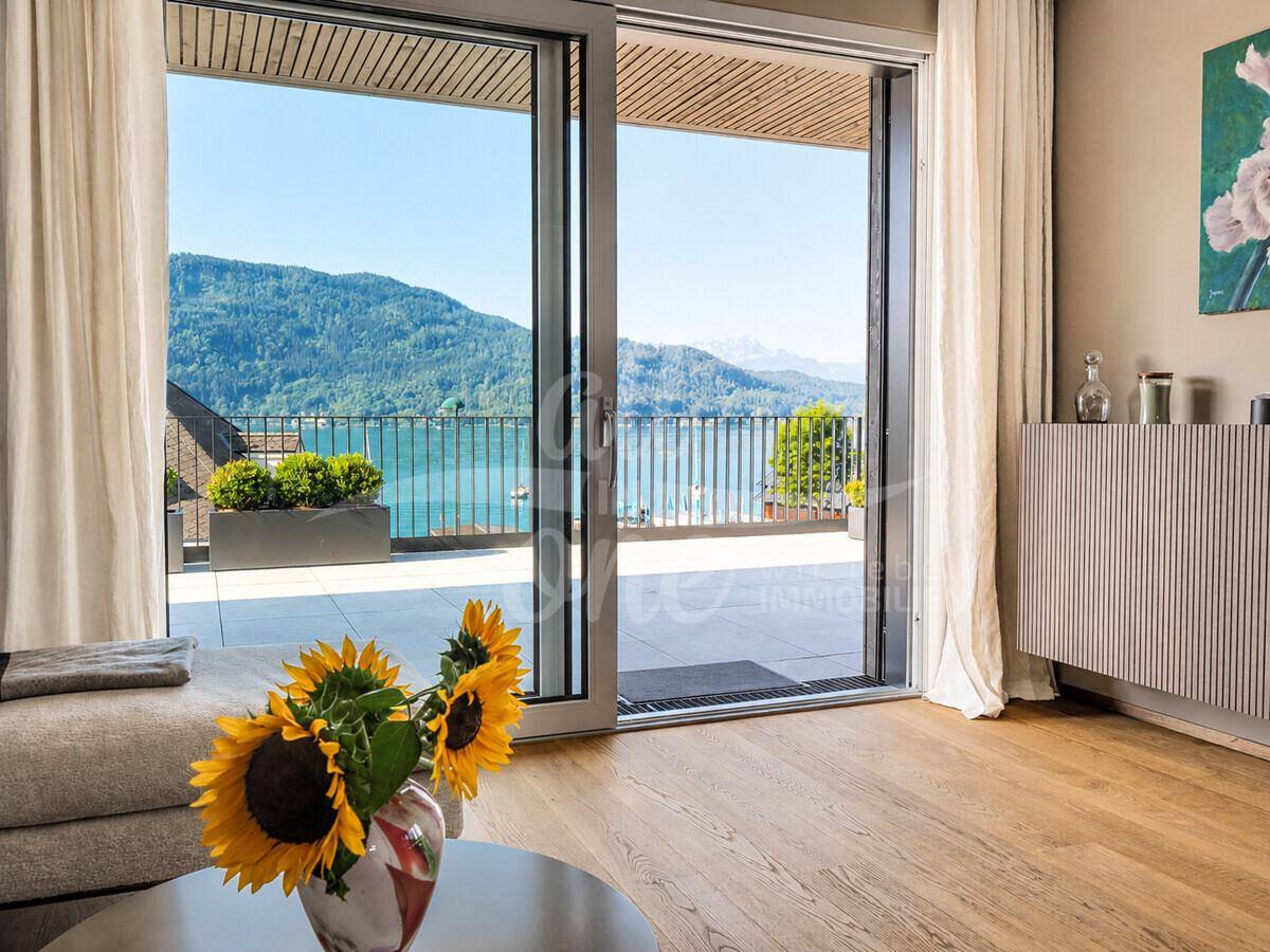 Großzügige Fensterfront im Wohnzimmer bietet einen weiten Blick auf den See und die Berge.