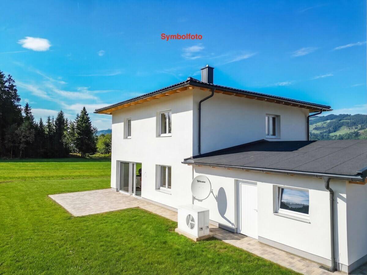 Seitenansicht des Hauses mit moderner Wärmepumpe und Zugang zur Terrasse im Grünen.