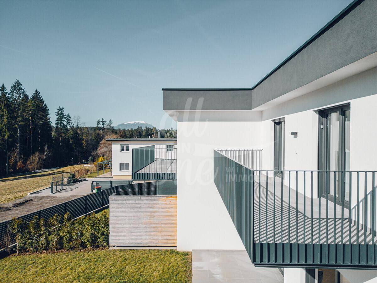 Moderner Balkon mit Metallgeländer und weitem Blick auf die umliegende Landschaft und Berge.