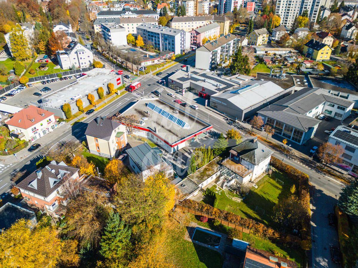 Luftaufnahme des Geschäftsgebäudes und der umliegenden städtischen Bebauung mit viel Grün und Parkplätzen.