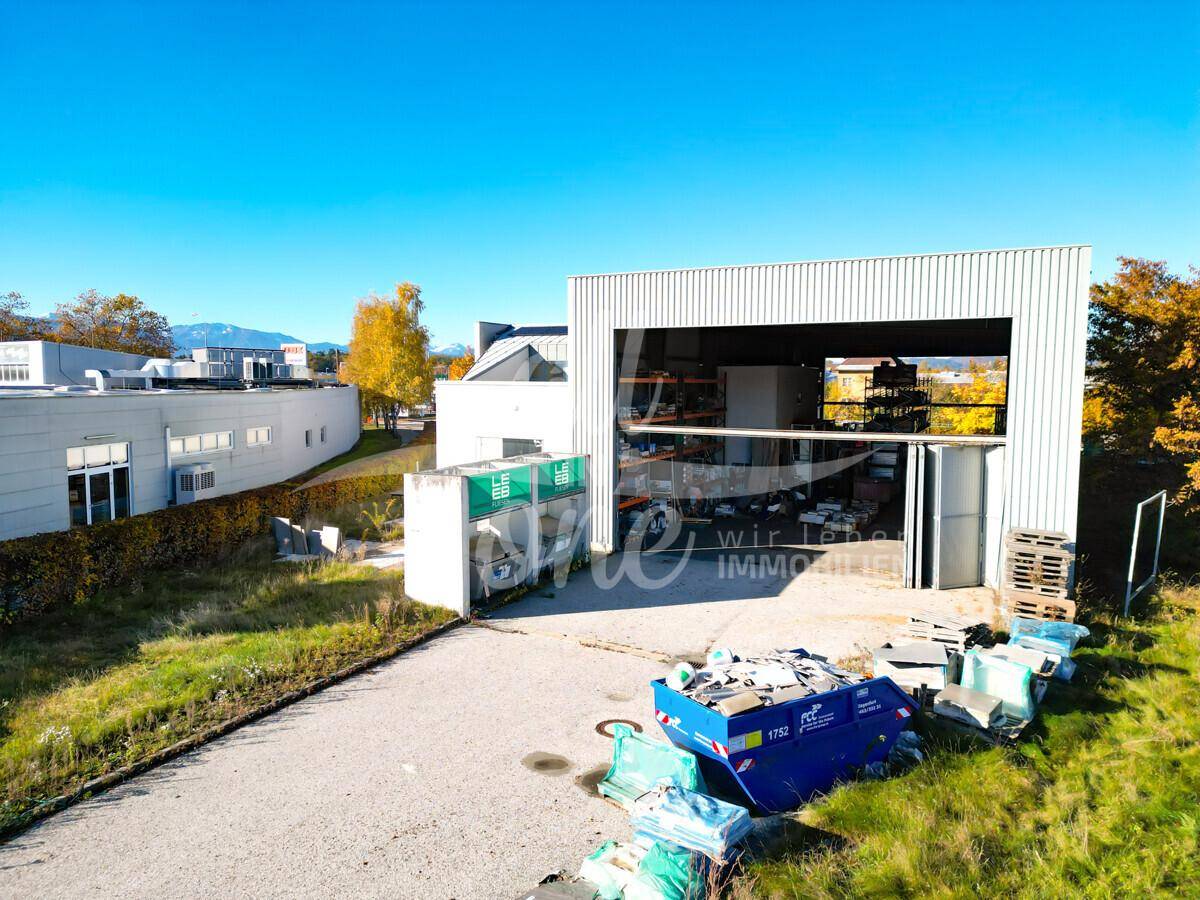 Rückseite eines Gewerbegebäudes mit offener Ladezone und Containern im Vordergrund.
