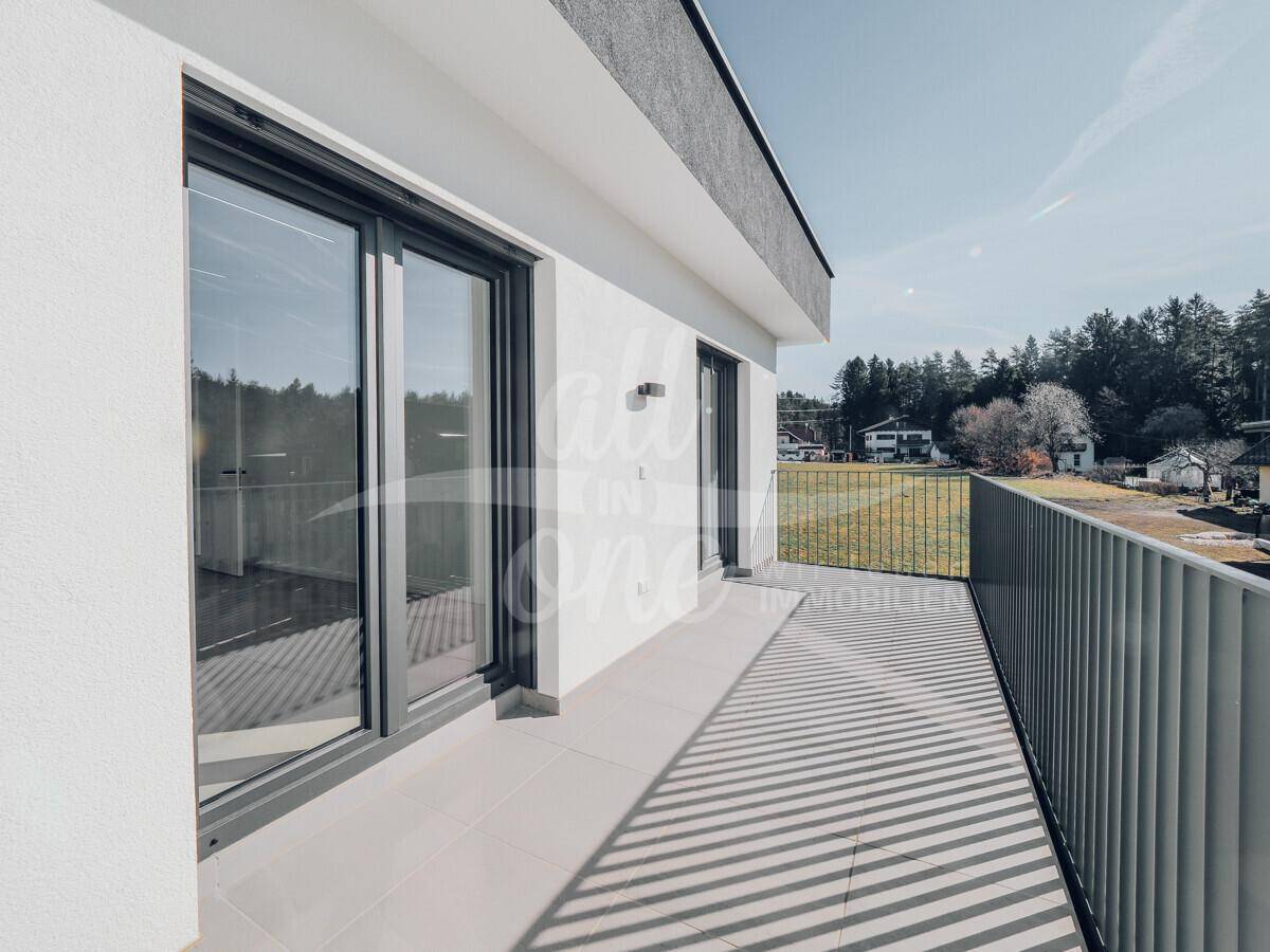 Moderner Balkon mit Fliesenboden und Metallgeländer, bietet einen weiten Blick ins Grüne.