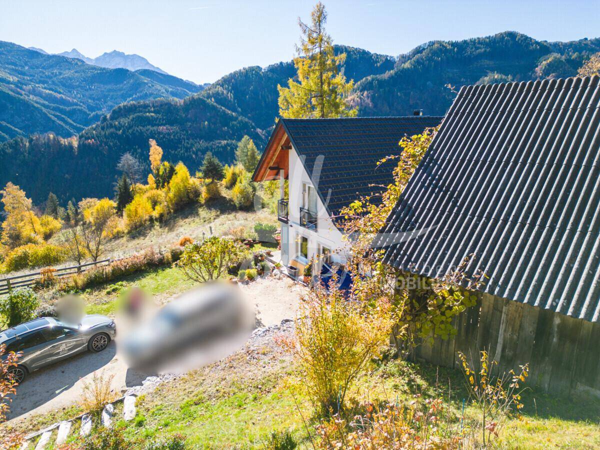 Haus und Nebengebäude mit Einfahrt und beeindruckendem Panoramablick auf die umliegenden Berge.