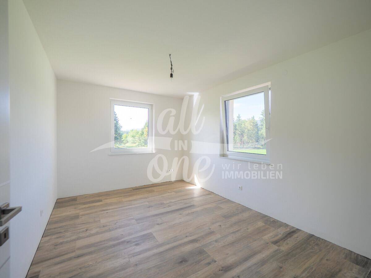 Helles Schlafzimmer mit Holzboden und zwei Fenstern, die einen schönen Ausblick bieten.