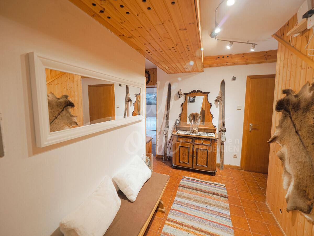 Rustikaler Eingangsbereich mit Holzdecke, Fliesenboden und traditionellen Dekorationen.