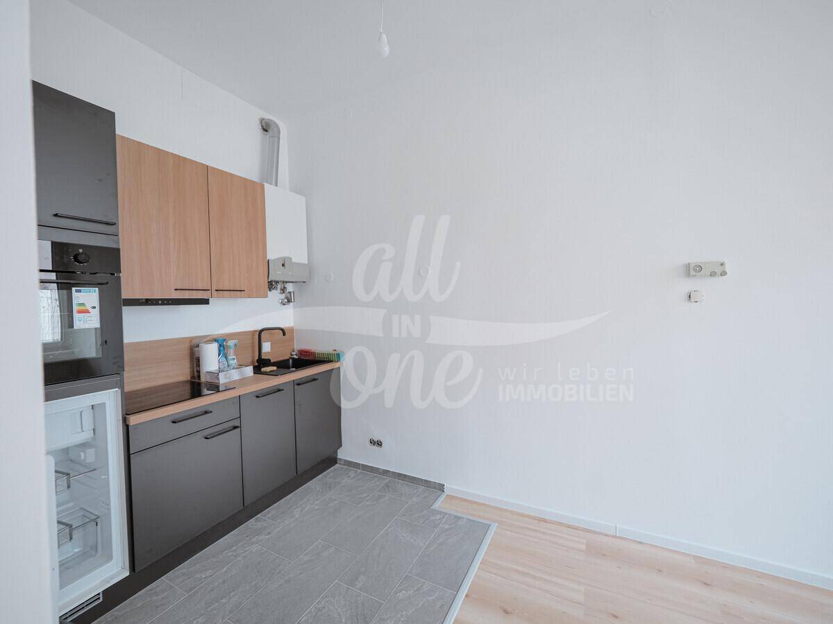 Moderne Küchenzeile mit Holz- und Anthrazitfronten, integrierten Geräten und Fliesenboden.