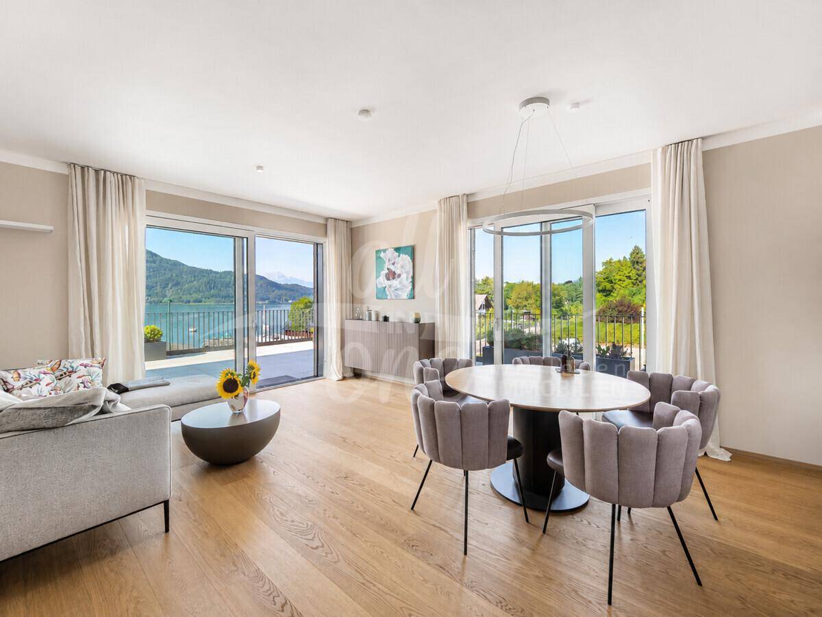 Heller Wohn-Essbereich mit Holzboden, großen Fenstern und direktem Zugang zur Terrasse mit Seeblick.