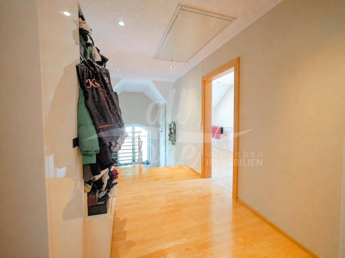 Heller Flur im Obergeschoss mit Holzfußboden, Garderobe und Blick auf die Treppe.