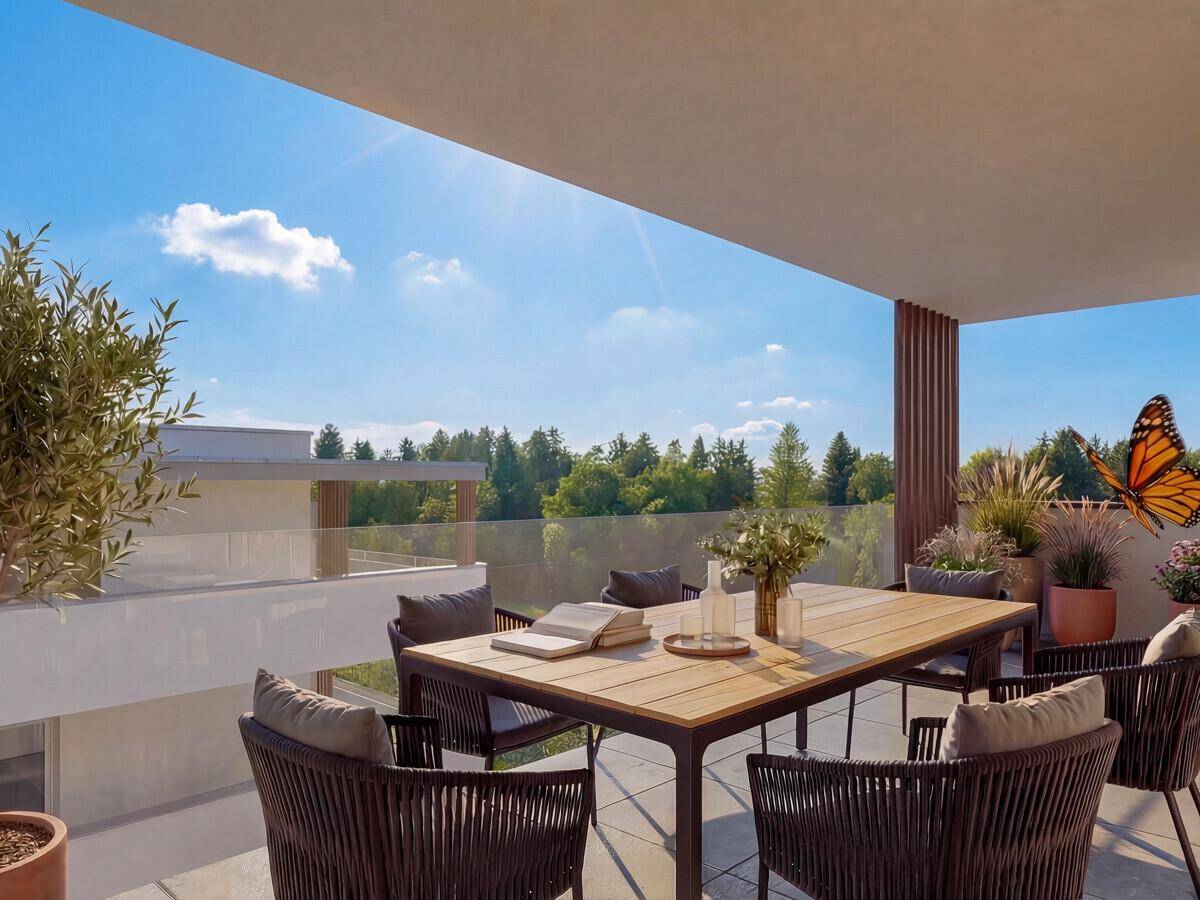 Geräumige Terrasse mit Esstisch und Stühlen, umgeben von Grün und unter blauem Himmel.