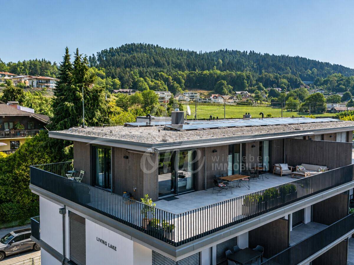 Moderne Architektur des Gebäudes mit mehreren Terrassen und Gründach, umgeben von grüner Landschaft.