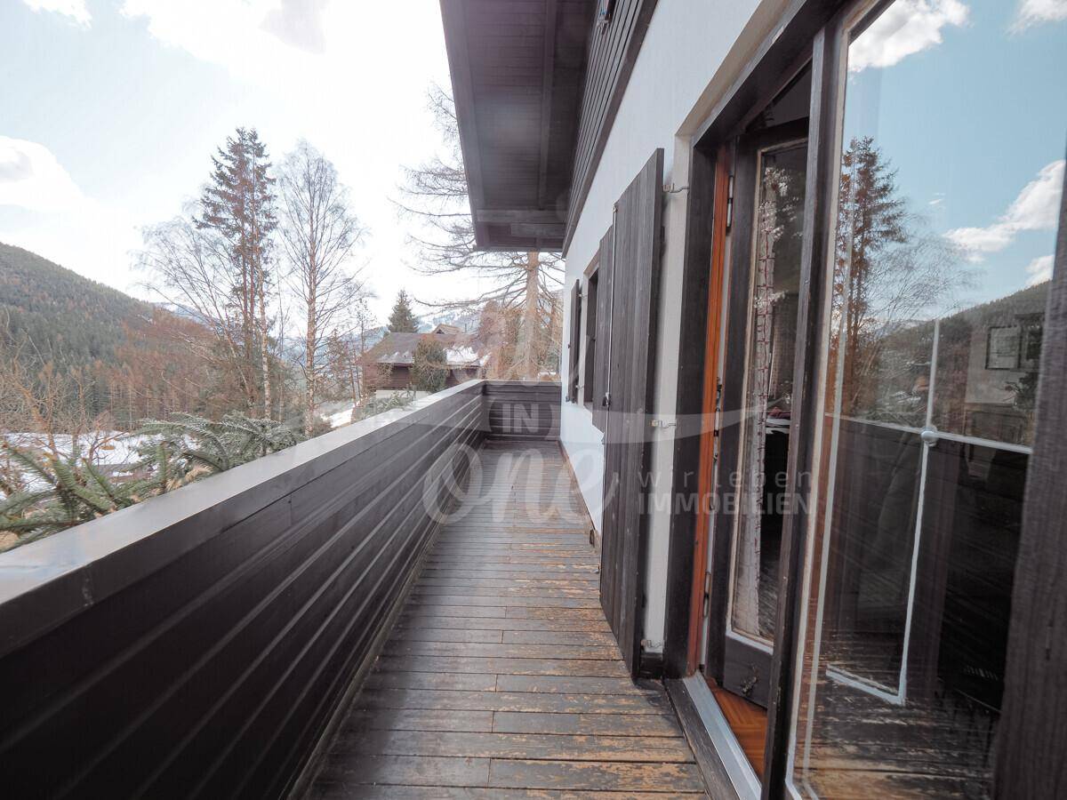 Langer Holzbalkon mit Blick auf die umliegende Berglandschaft.