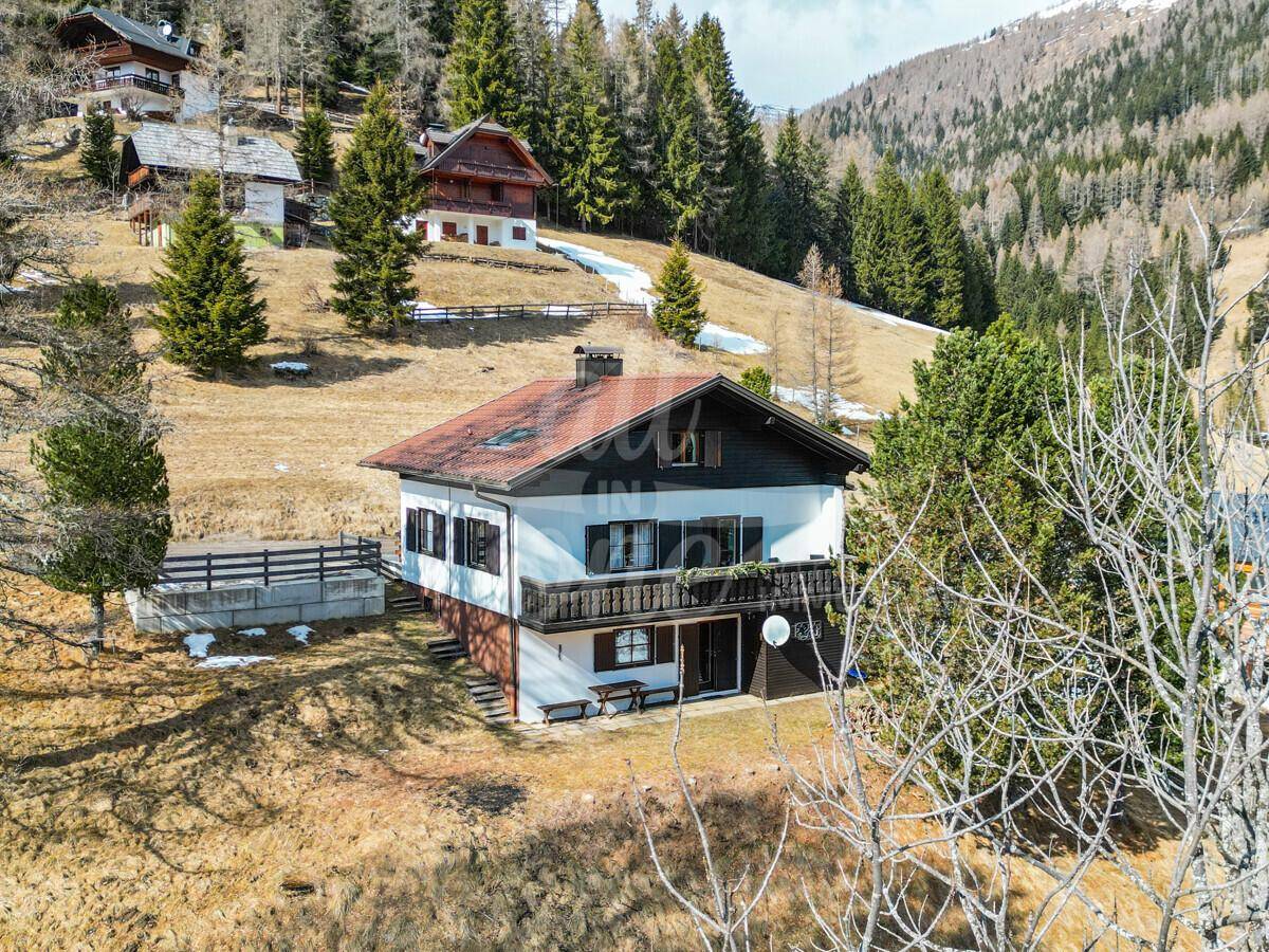 Traditionelles Haus in alpiner Umgebung mit Balkon, grüner Wiese und Bergblick.
