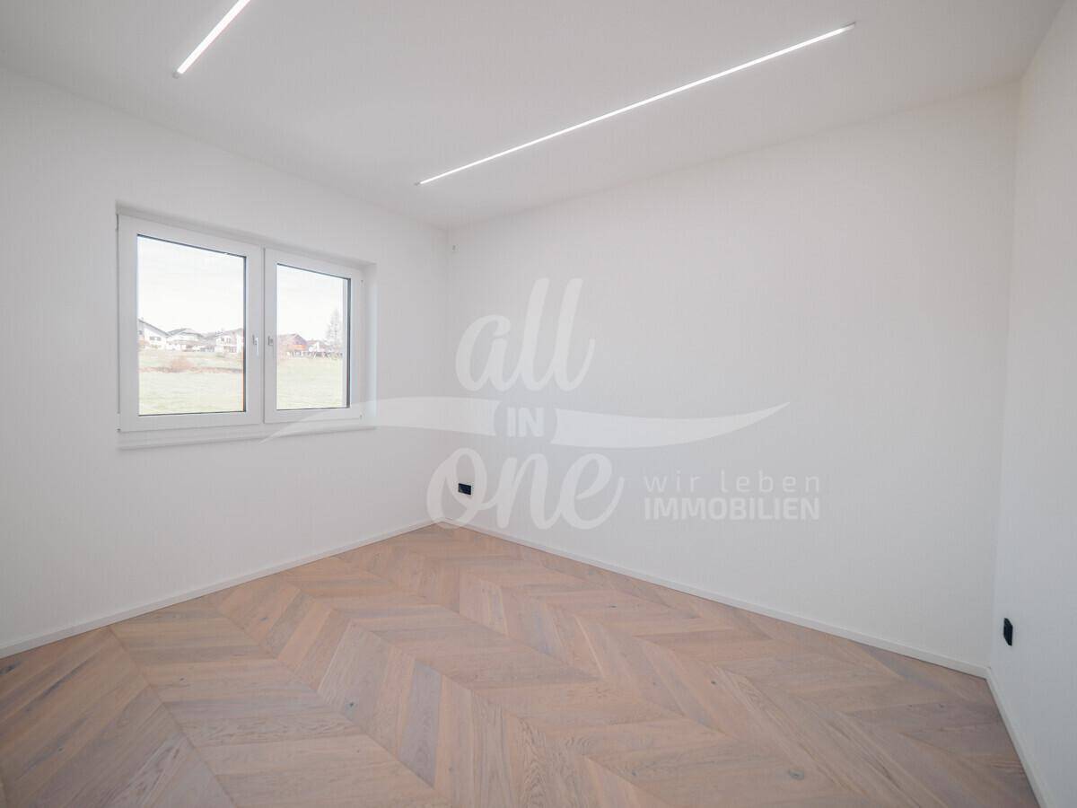 Helles Schlafzimmer mit Fischgrätparkett und großen Fenstern mit Blick ins Grüne.