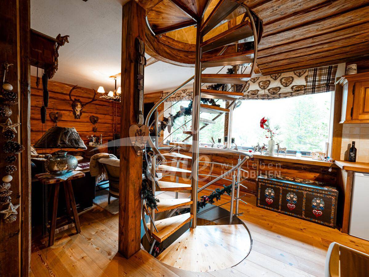 Heller Wohnbereich mit Wendeltreppe, Holzwänden und großen Fenstern mit Blick ins Grüne.