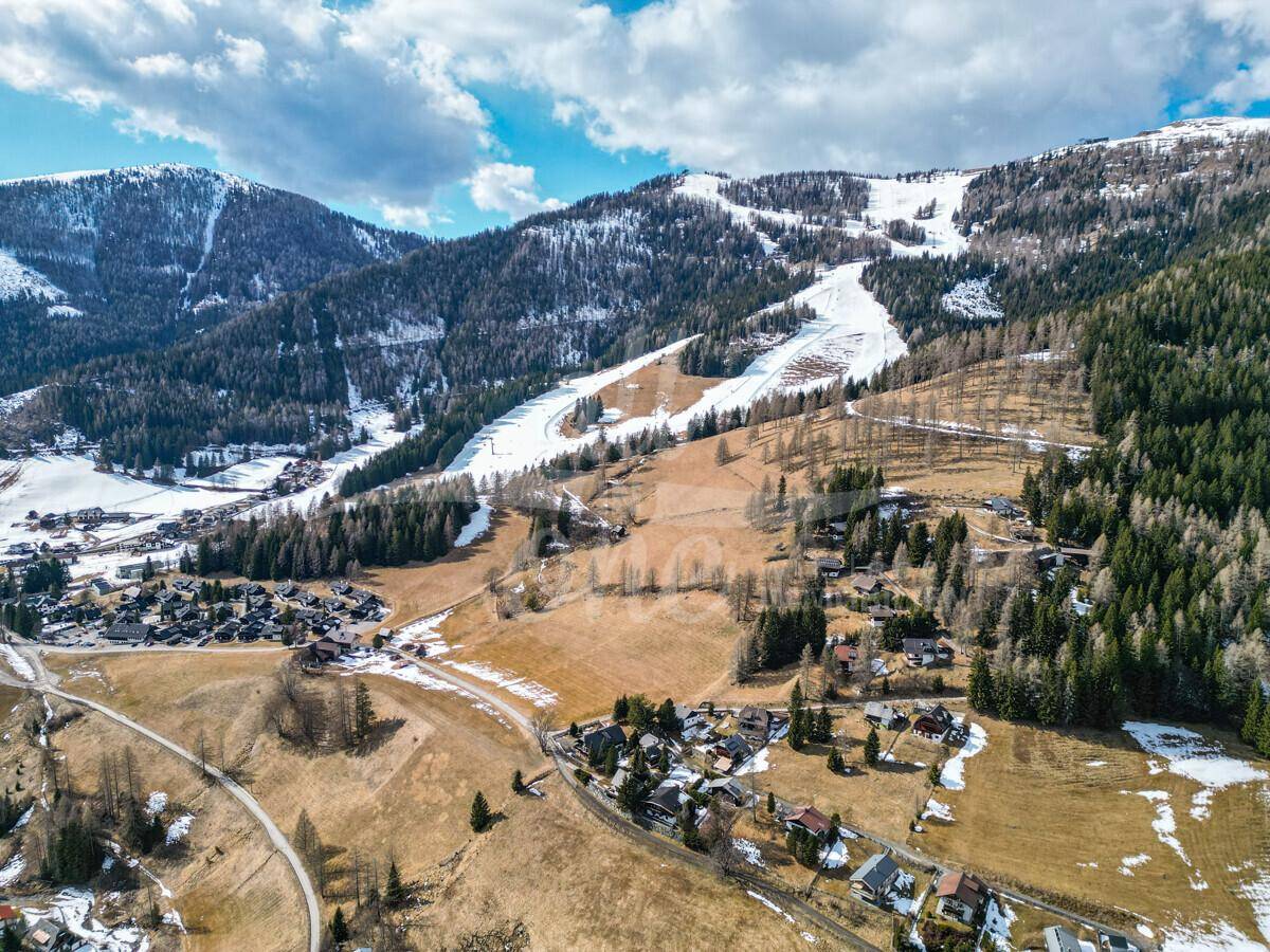 Weitläufige Luftaufnahme der Berglandschaft mit Skigebiet und Siedlungen.