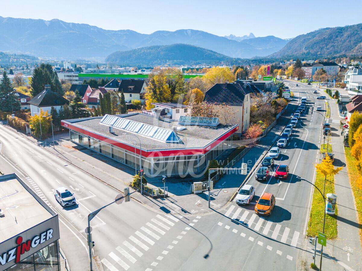Weitläufige Luftaufnahme des Geschäftsgebäudes an einer Kreuzung mit umliegenden Straßen und Bergen im Hintergrund.
